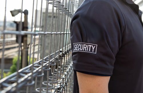 A view of a security guard in uniform patrolling a residential area nearby railway.